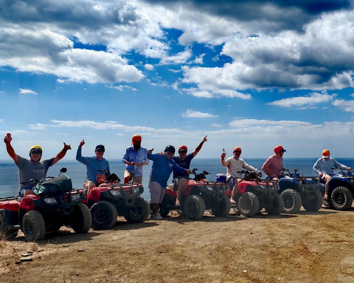 Grupo de viajeros celebrando en ATV con vista al océano